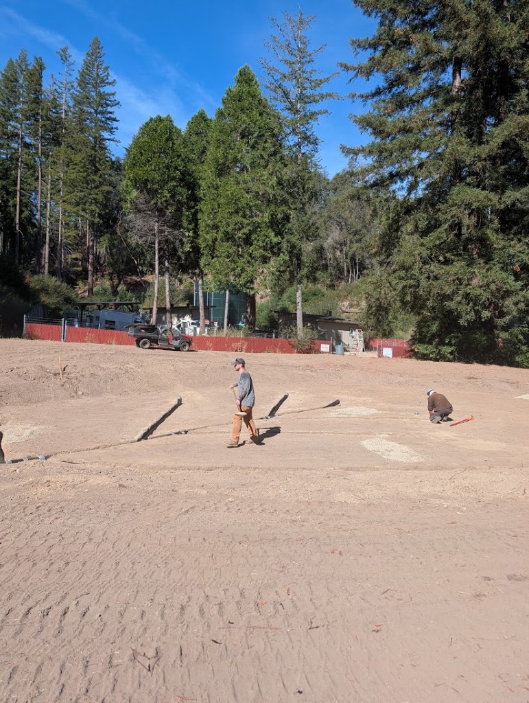 Two crew members working drainage lines on a shaped green