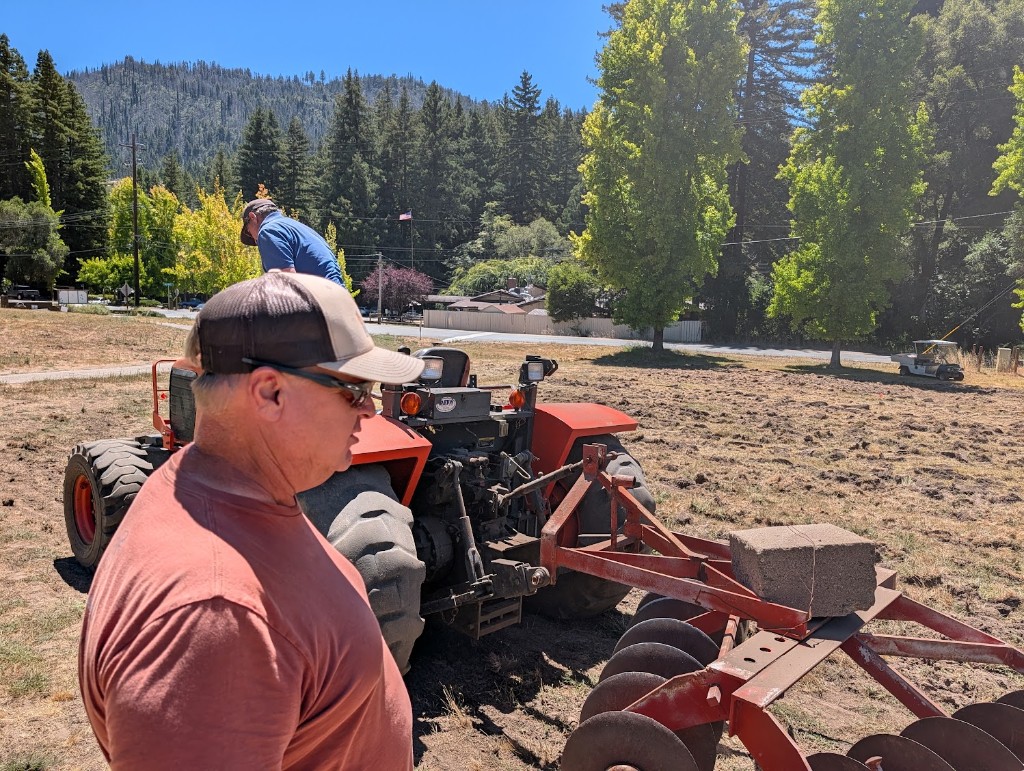 Crew discing the 10th fairway with an orange tractor and disc harrow