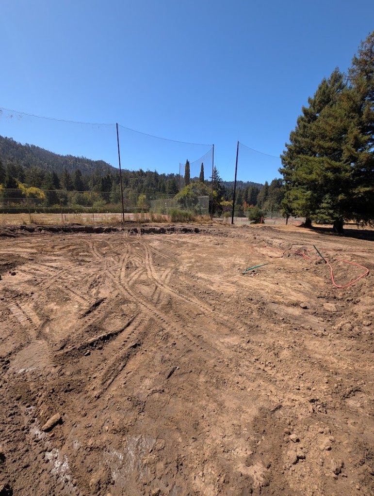 Hole 12 green after initial excavation, with safety netting and redwoods beyond