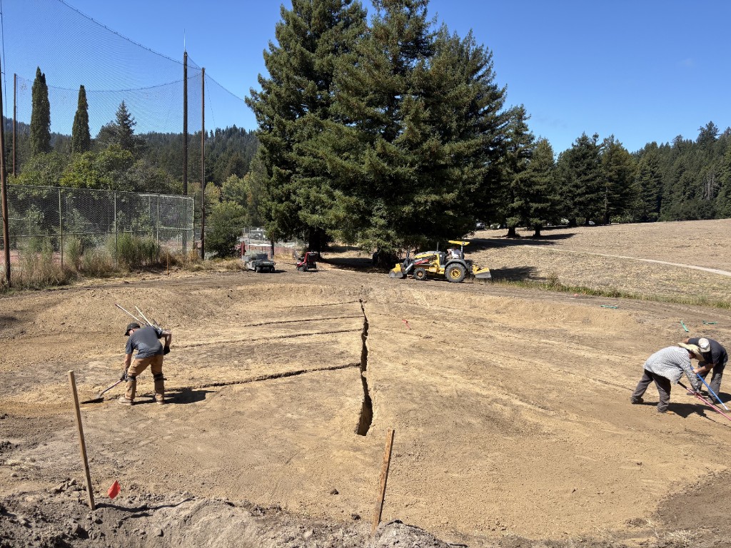 Crew hand-trenching a shaped green for drainage pipe