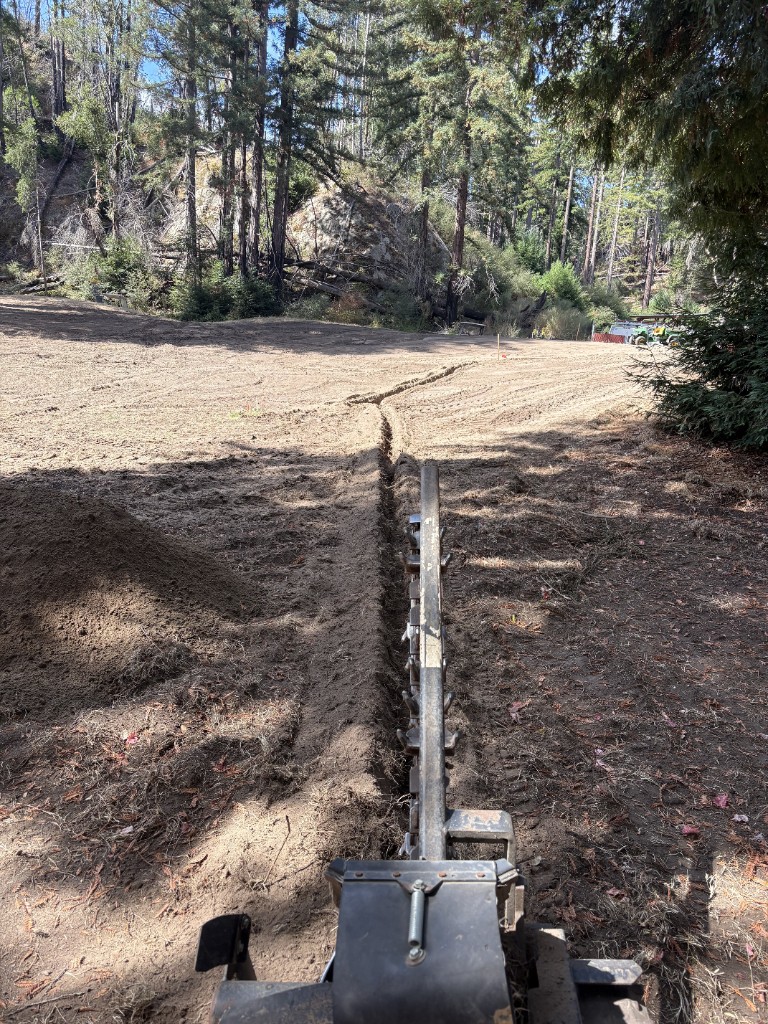 Trencher cutting a drainage channel across a shaped green