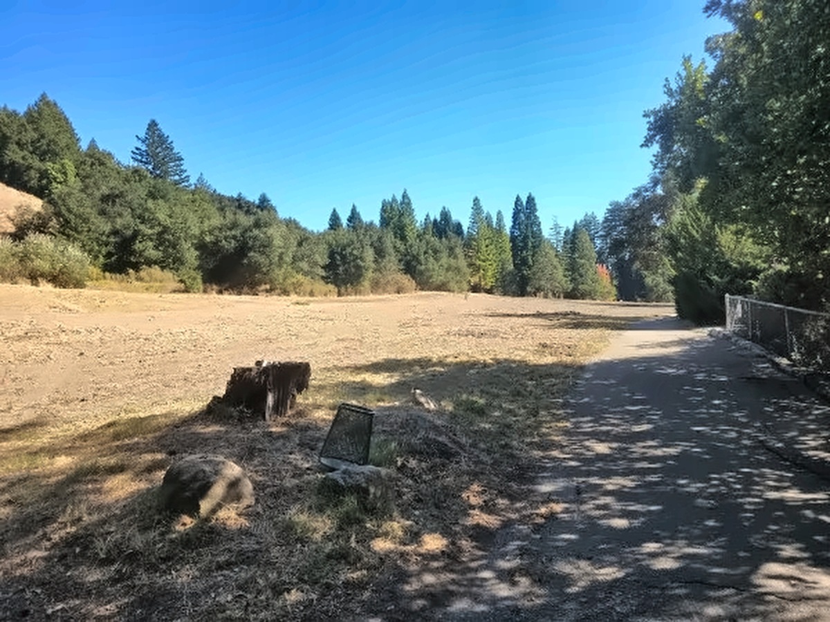 The wide, graded 12th fairway beside the cart path, with a tree line and hills beyond