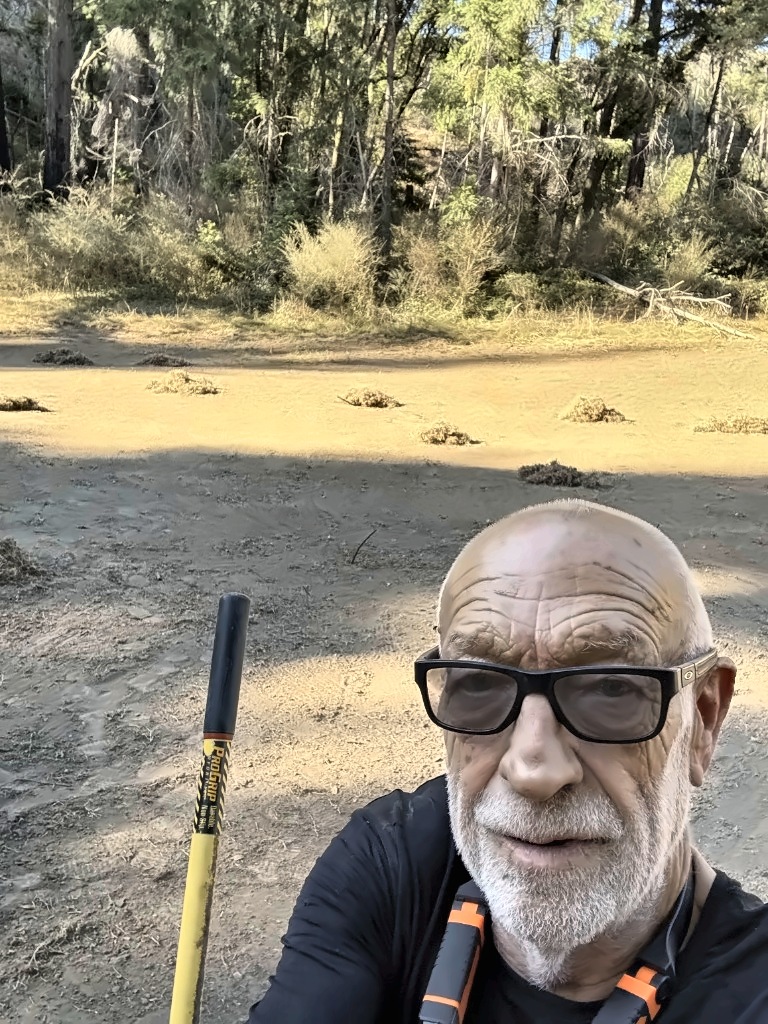 Jerry Lester taking a selfie with his rake on the 17th fairway, rake piles dotting the ground behind him