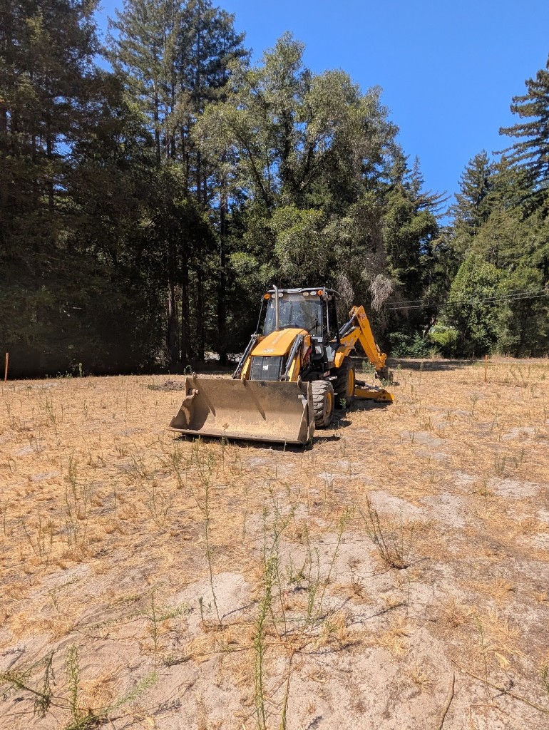 Yellow backhoe loader on the back nine worksite