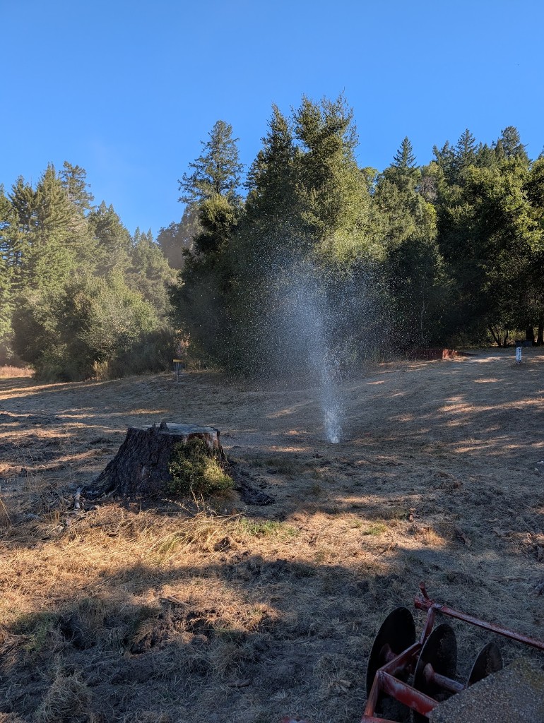 Water spray testing irrigation on the back nine with a stump and disc in the foreground